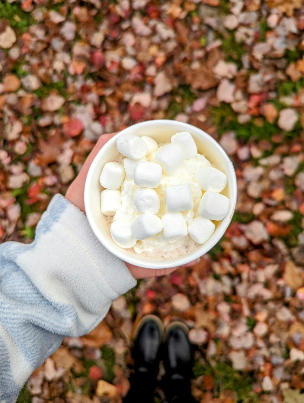 a person holding a cup with marshmallows in it