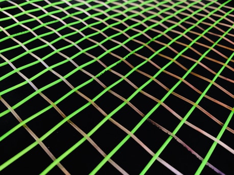 A grid pattern of evenly spaced, thin, fluorescent green lines against a black background, creating an optical illusion effect.