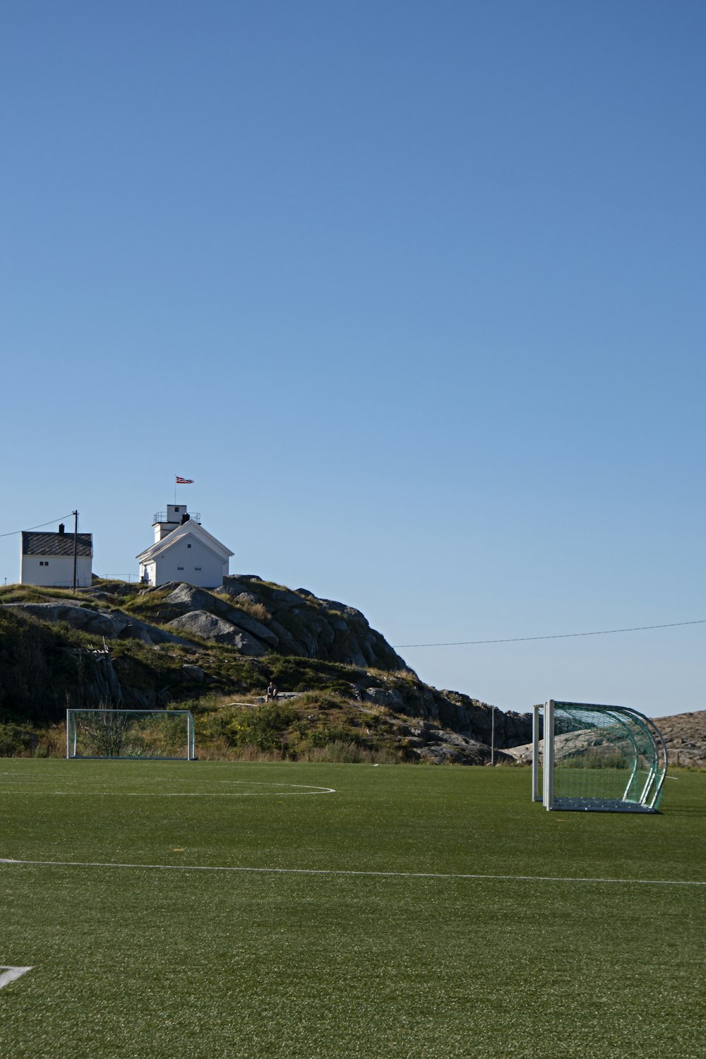 a soccer field with a soccer goal and a lighthouse in the background