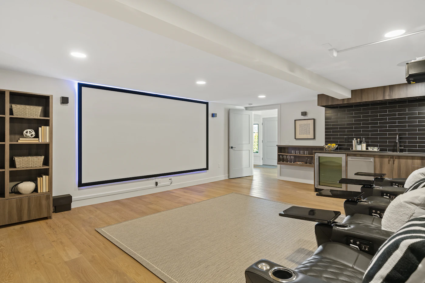 A finished media room with a fixed projection screen and tiered leather recliner seating