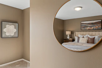 A tall, elegant full-length mirror with a soft beige frame in a minimalist bedroom.