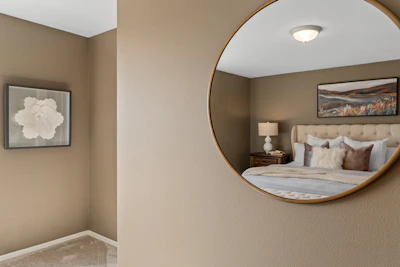A tall, elegant full-length mirror with a soft beige frame in a minimalist bedroom.