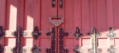 Close-up of a wooden door coated with rich, glossy industrial paint in deep red.