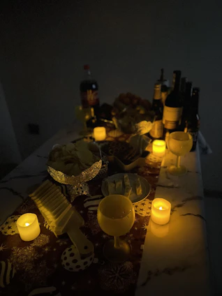 Artfully arranged gourmet snacks and wine bottles on a sleek glass table with soft lighting