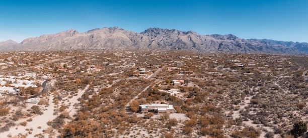 A wide-open plot of land with desert landscaping and mountain views under a clear blue sky in Queen Creek.