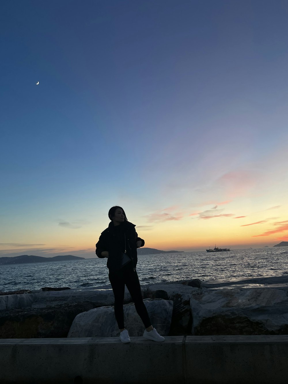 a person standing on a rock near the ocean