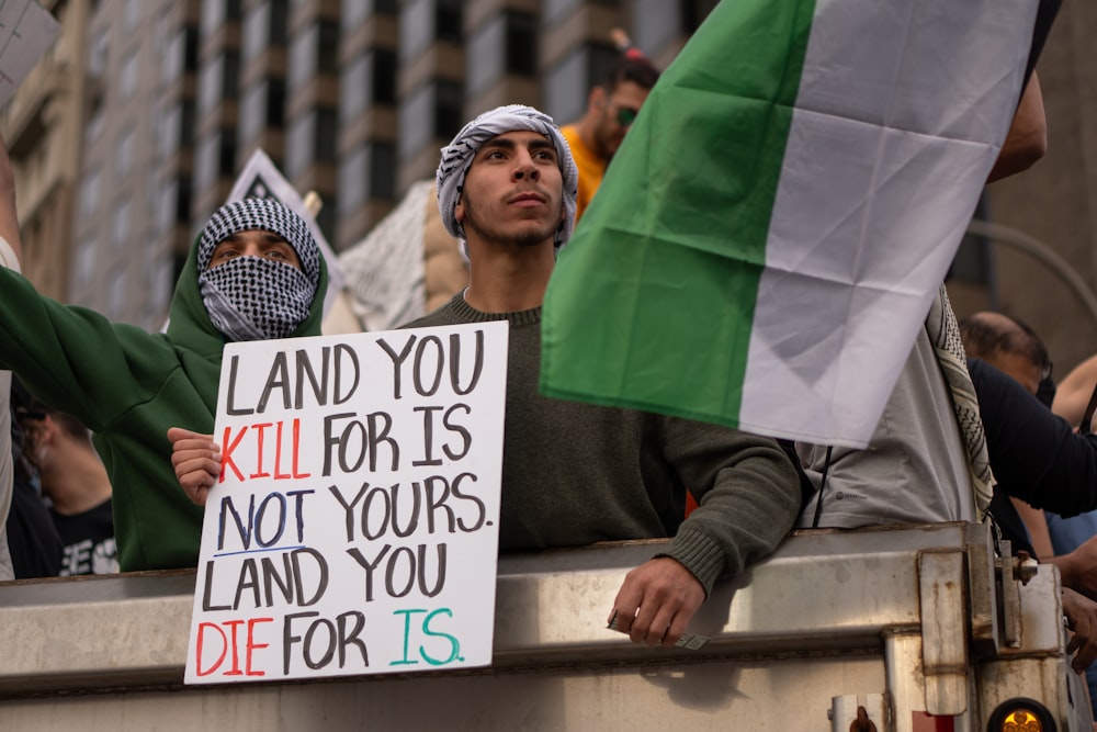 a man holding a sign in the back of a truck