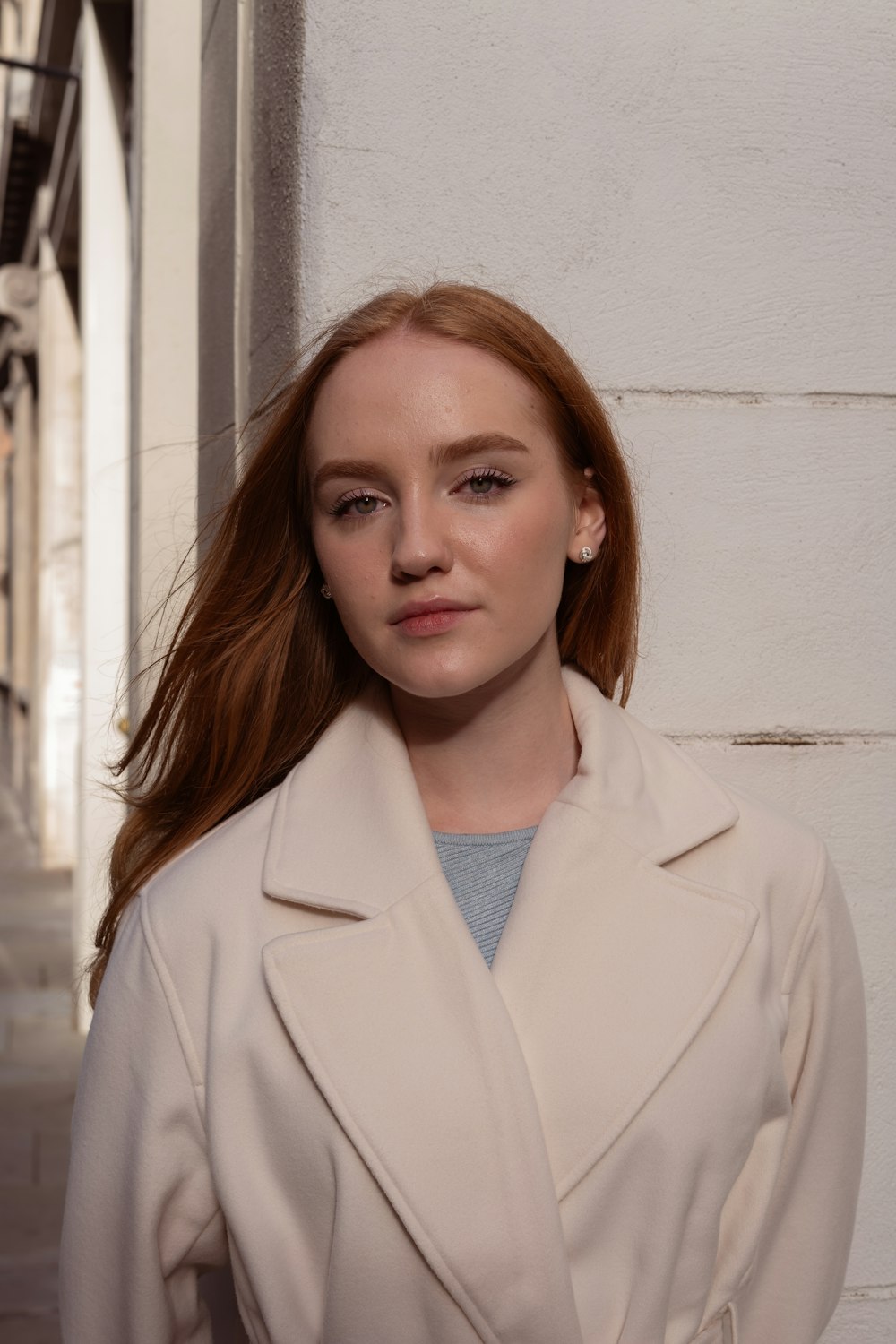 a woman with red hair standing in front of a white wall