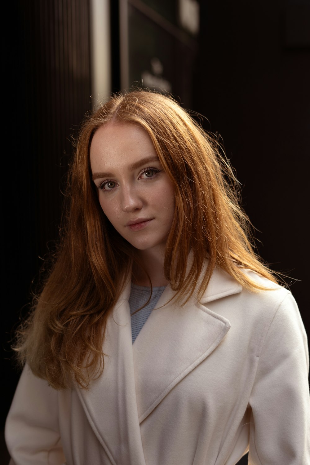 a woman with long red hair wearing a white coat