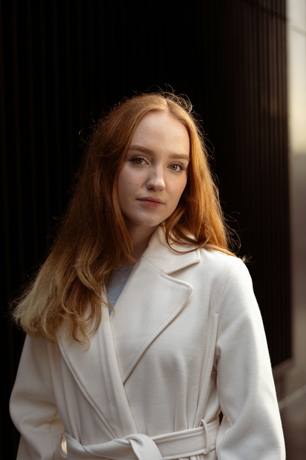 a woman with red hair wearing a white coat