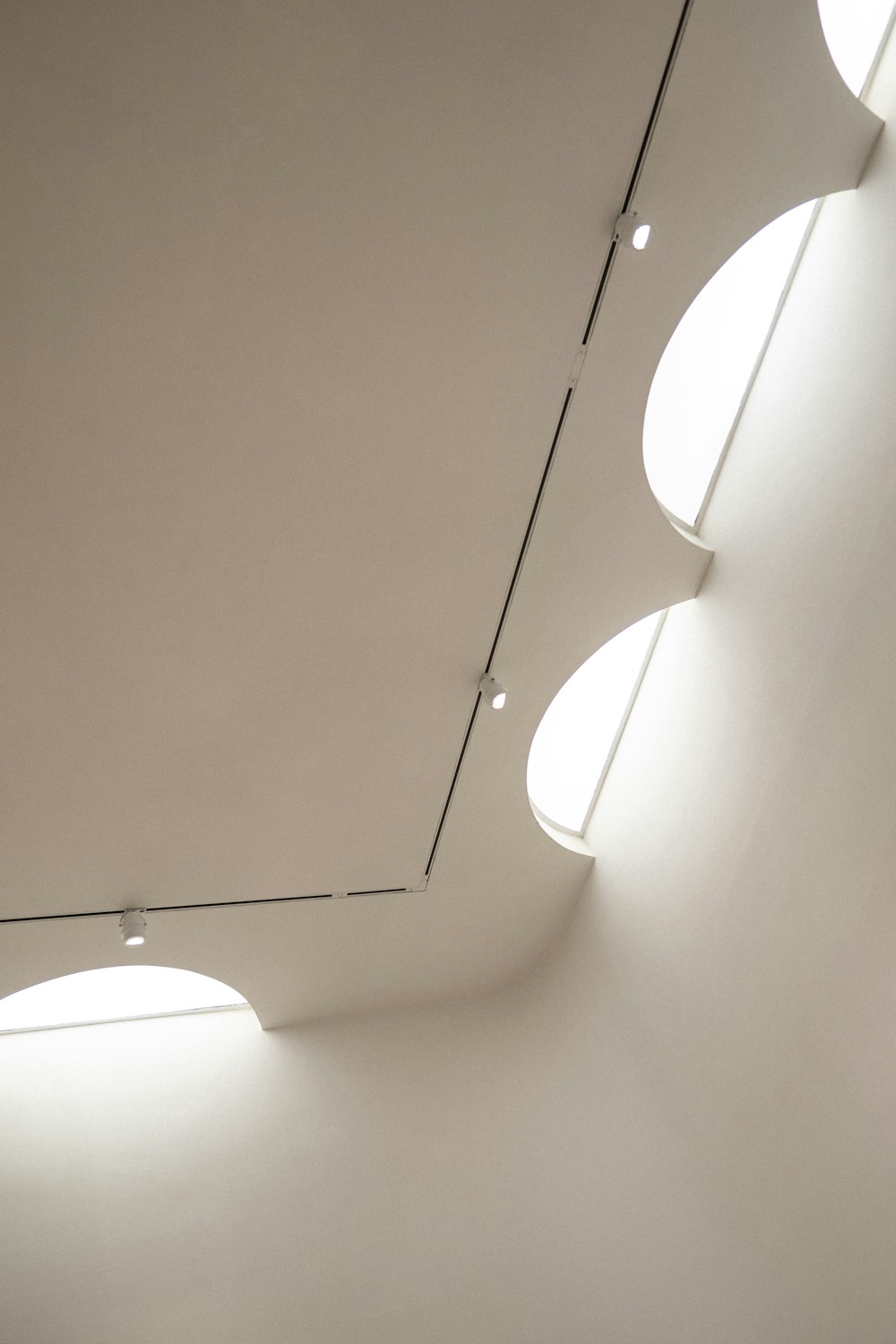 uma sala branca com três luzes redondas no teto