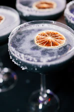 A close-up of a colorful craft cocktail garnished with fresh herbs and citrus.