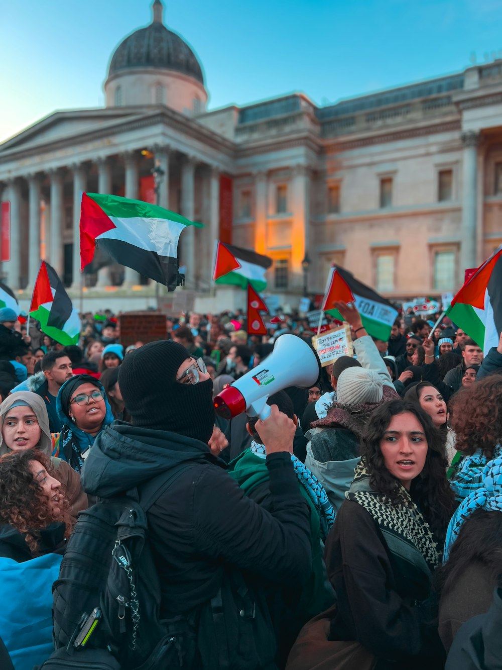 a large group of people with flags in front of a building