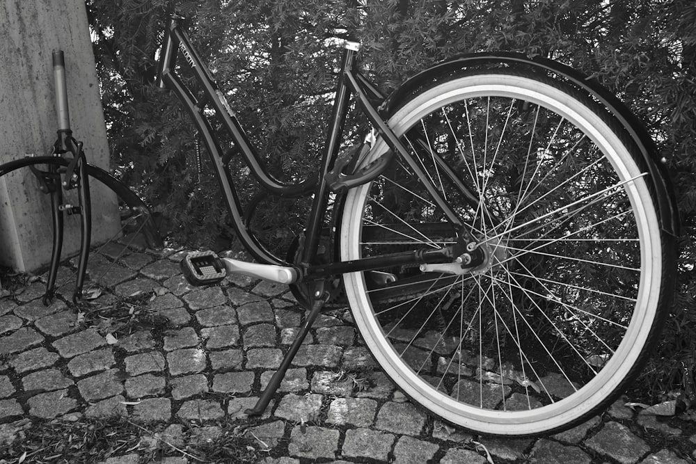 a black and white photo of a bicycle leaning against a wall