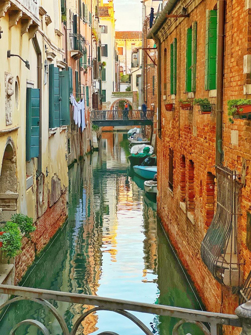 a narrow canal running between two buildings with green shutters