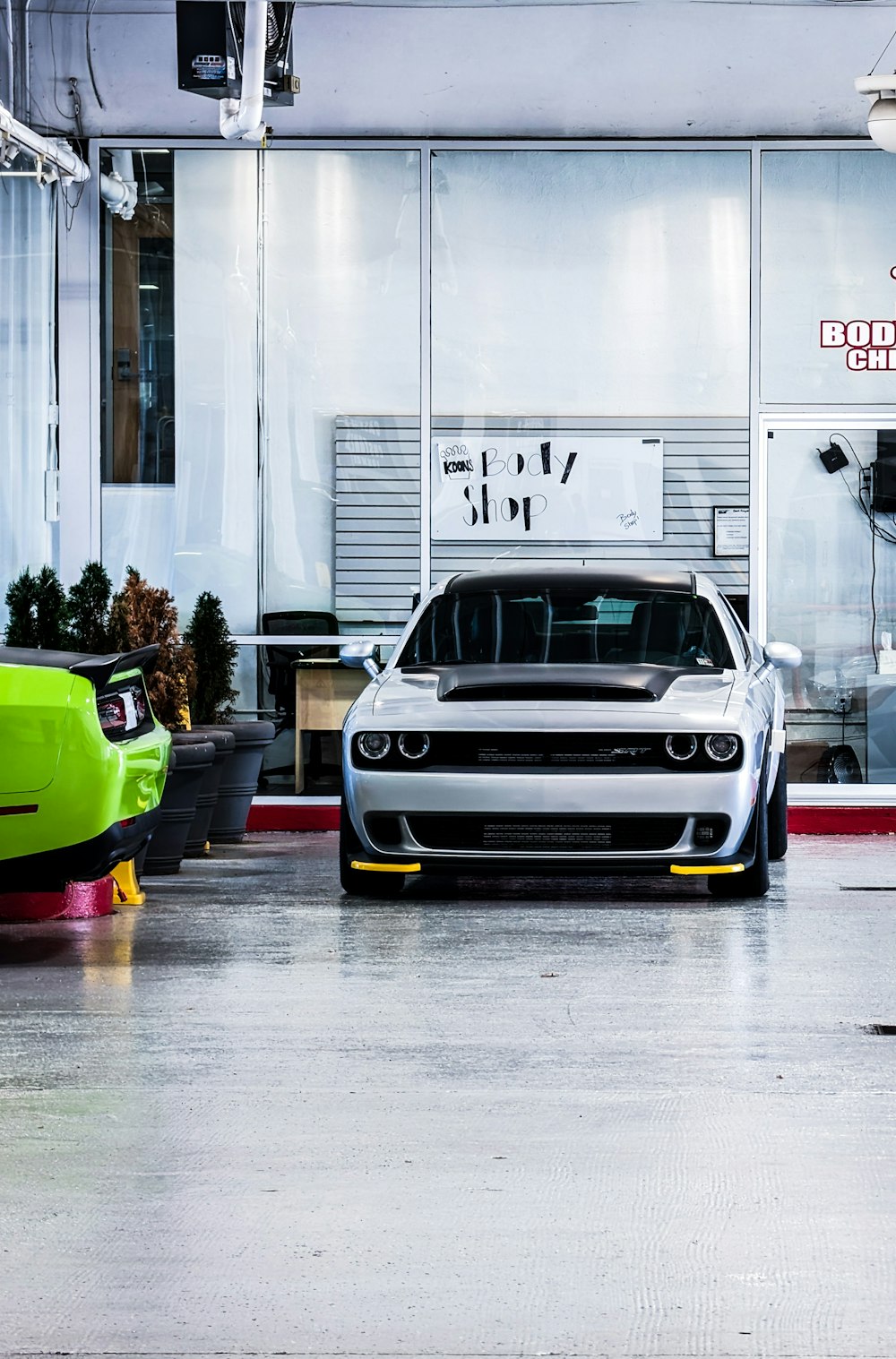 a white car parked in a garage next to a green car