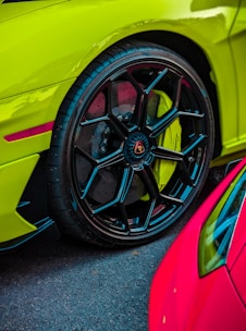 A set of sporty car rims stacked beside a tire shop entrance with vibrant colors.