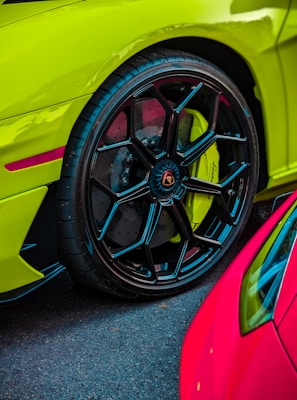 A set of sporty car rims stacked beside a tire shop entrance with vibrant colors.