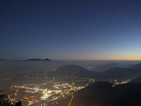 A panoramic view of a rugged quarry site transitioning into a sleek city skyline at dusk.