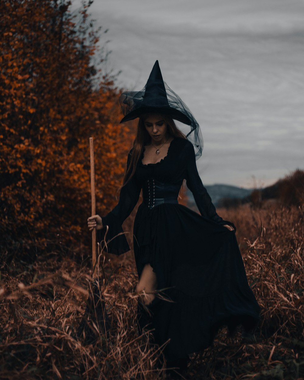 una donna in costume da strega che cammina attraverso un campo