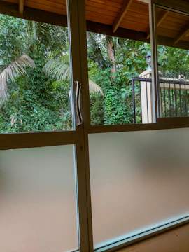 An elegant glass-paneled door framed by lush greenery, inviting natural light inside.