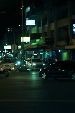 Nighttime shot of cars with colorful neon lights illuminating the scene.