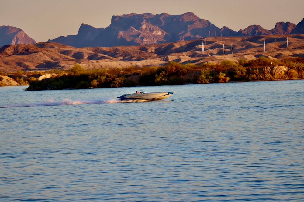a speed boat speeding across a lake with mountains in the background