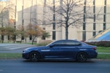 Sleek navy blue sedan parked in front of a modern building under clear skies.