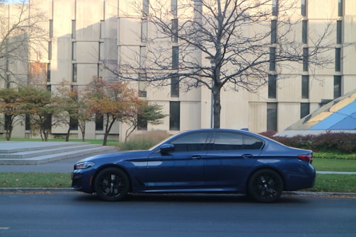A sleek new blue car parked outside a modern office building.