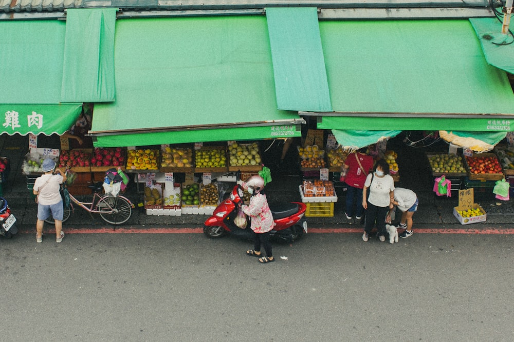 a group of people standing in front of a fruit stand