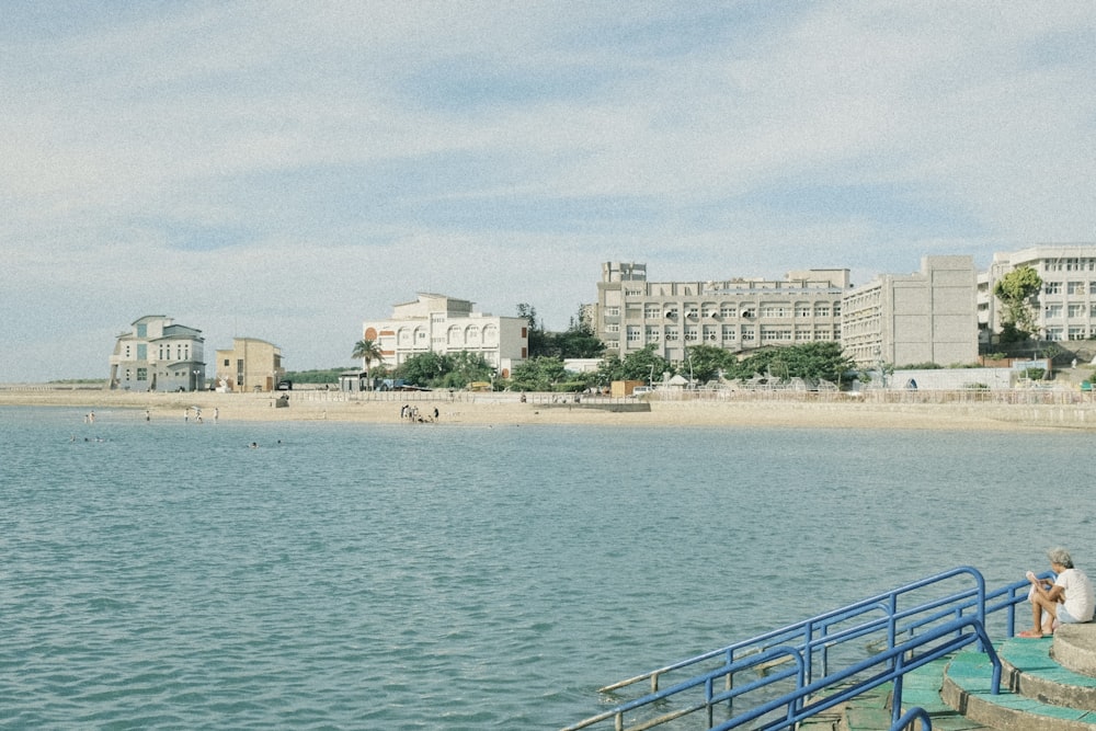 a couple of people sitting on a pier next to a body of water