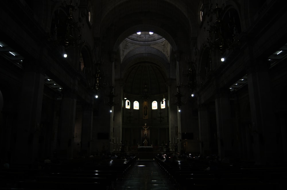 a dimly lit church with pews and stained glass windows