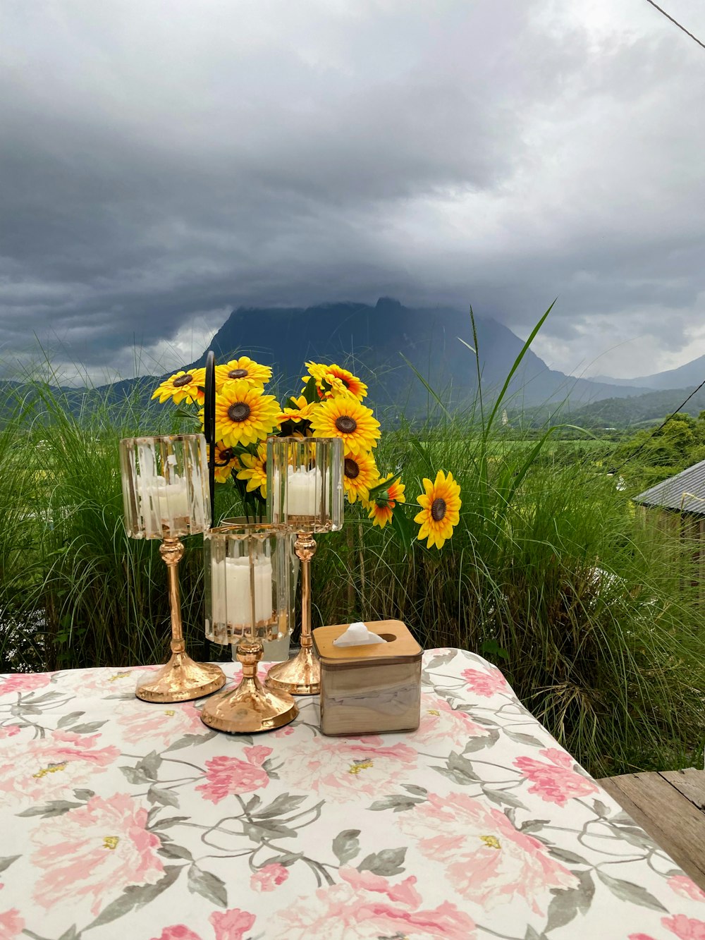 a table with a vase of sunflowers and candles on it