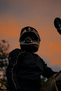Close-up of a biker's leather jacket with bold vėjasriba patches against a sunset backdrop.