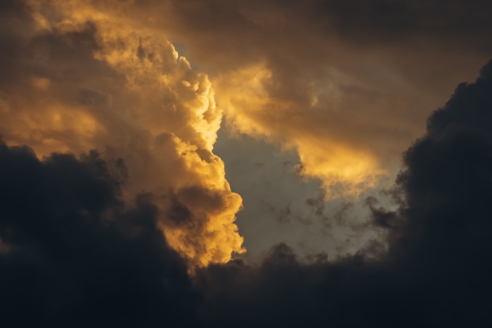 a plane flying through a cloudy sky at sunset