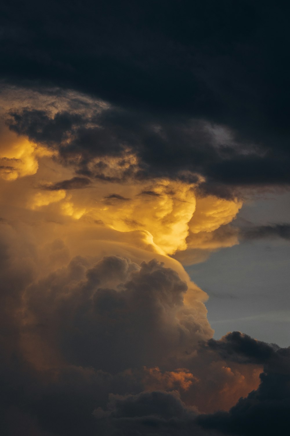 a plane flying through a cloudy sky at sunset