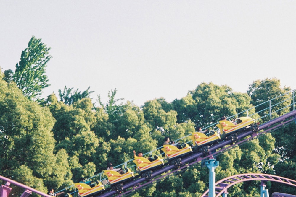 a roller coaster going down a hill with trees in the background