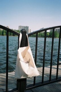A tote bag with bold Republican graphics hanging on a porch railing against a clear blue sky