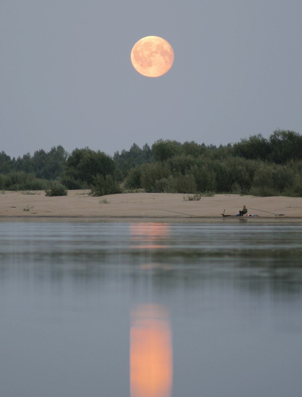 a full moon rising over a body of water
