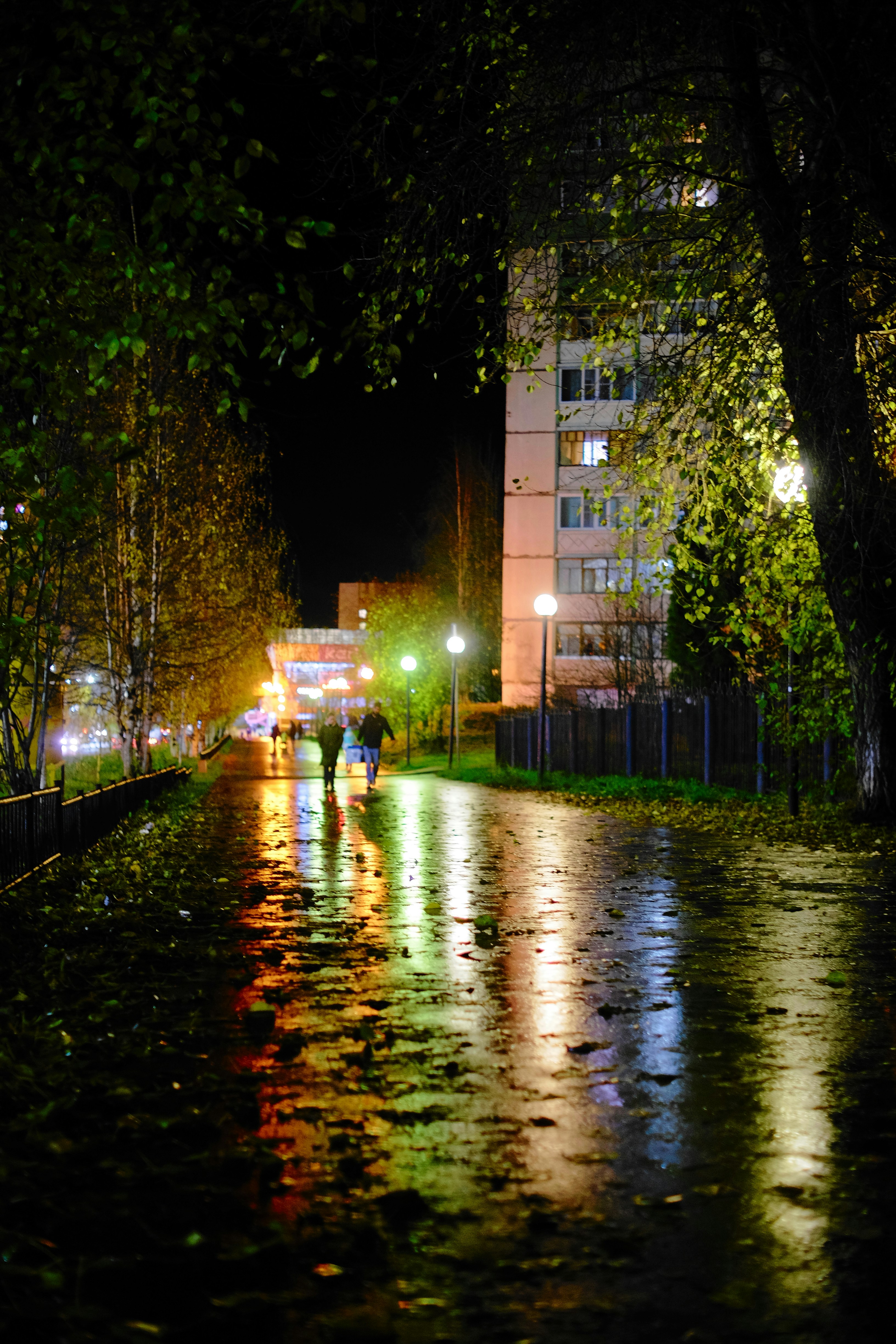 a couple of people walking down a street at night