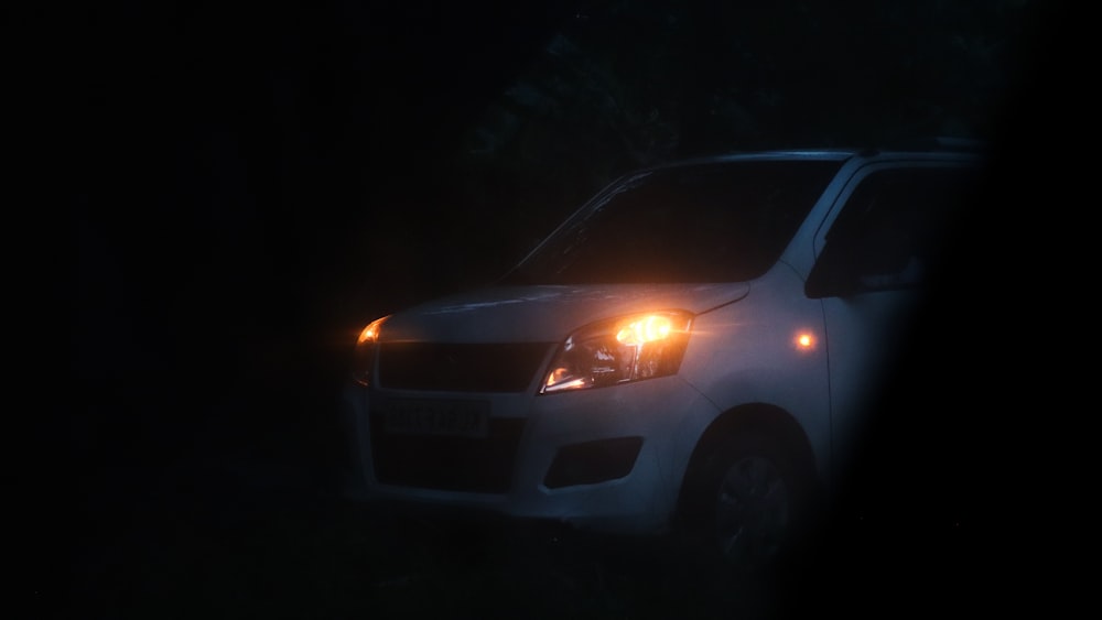 a white car with its lights on in the dark