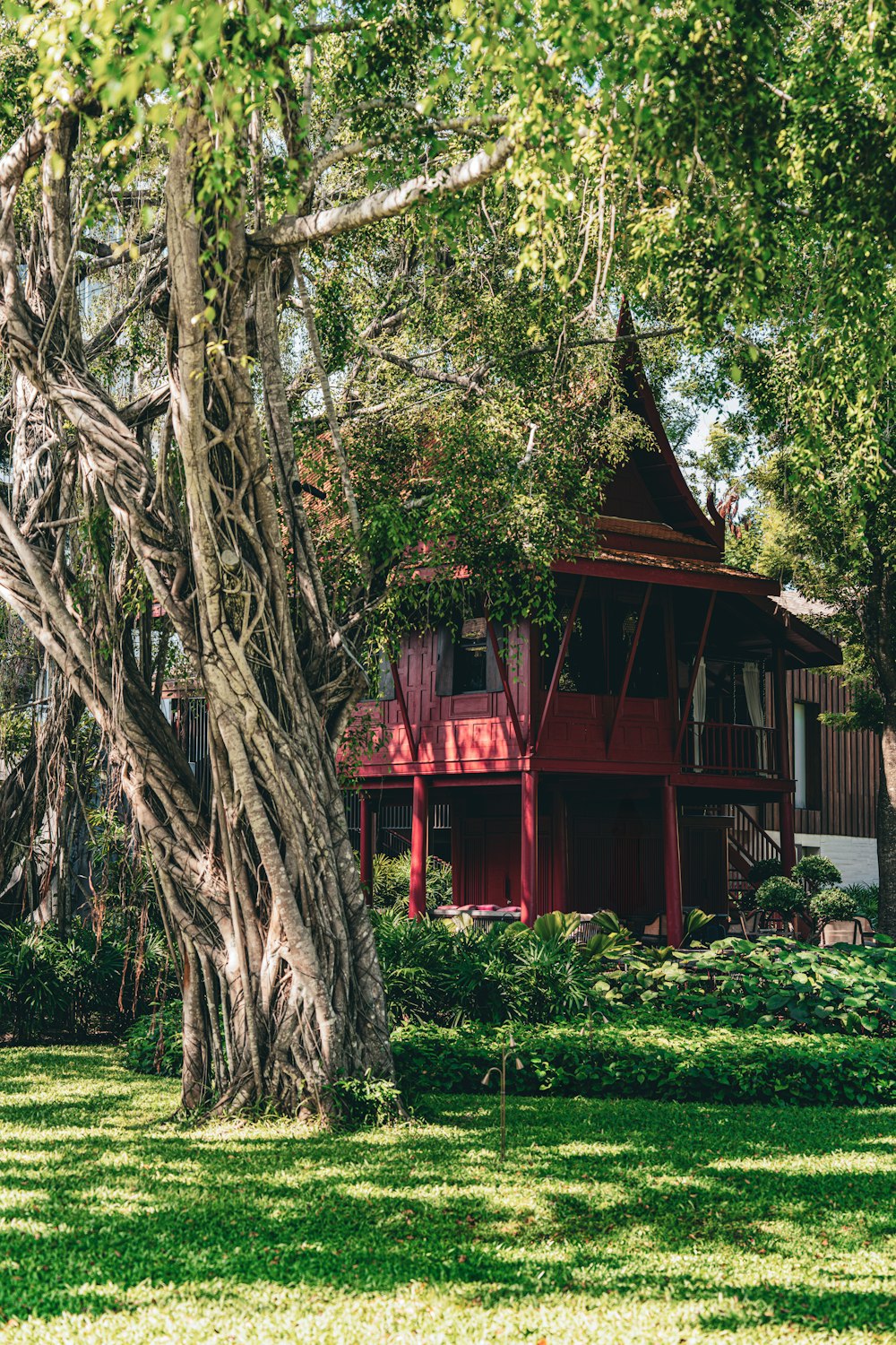 a red house sitting in the middle of a lush green field