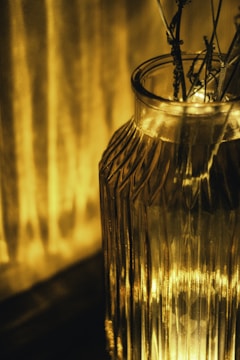 Elegant tall glass vase with delicate floral etching, glowing softly in natural light.