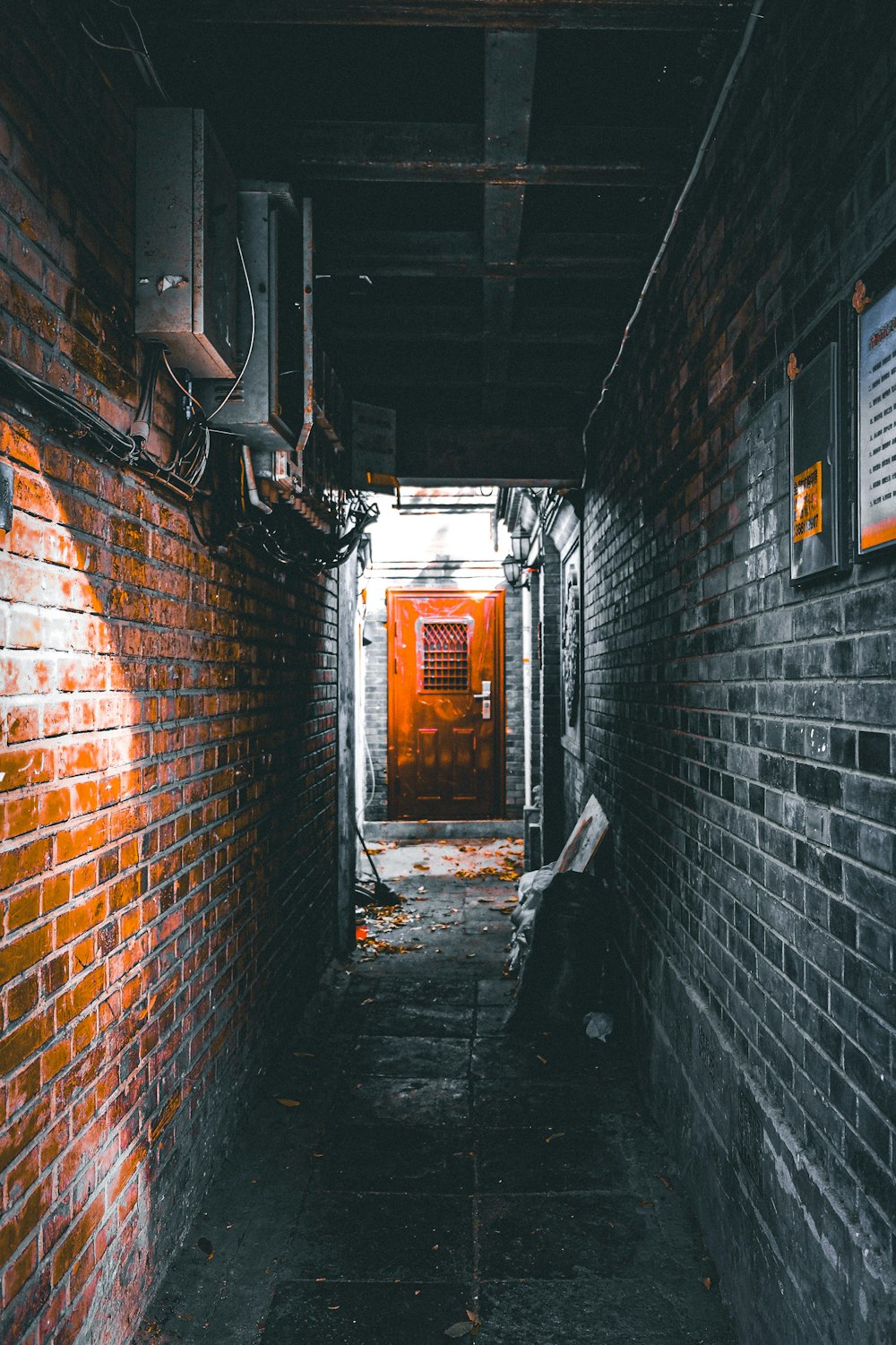 an alley way with a red door and brick walls