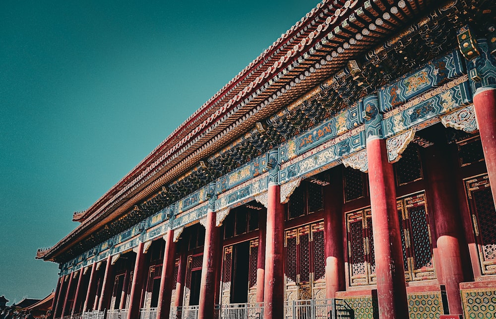 a tall building with red pillars and a blue sky in the background