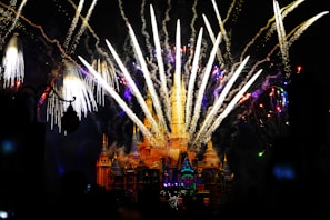 A magical nighttime castle illuminated with colorful fireworks bursting overhead