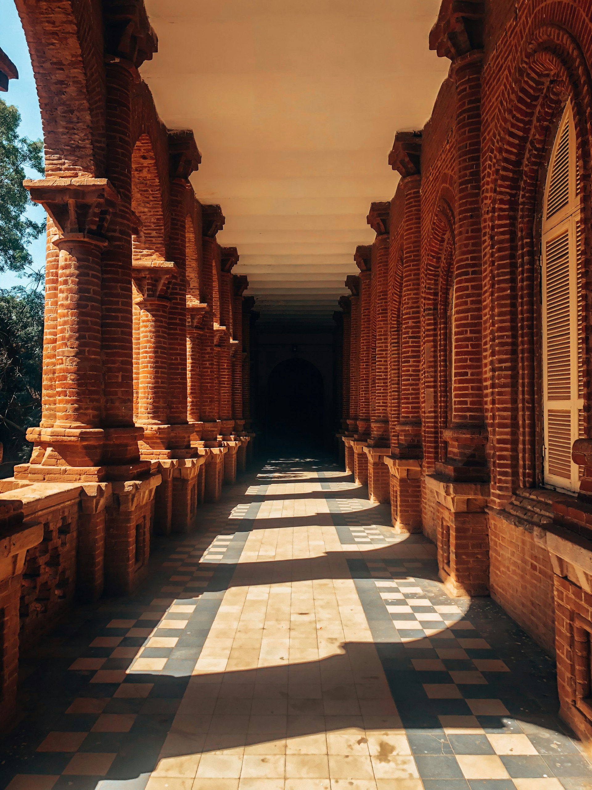 a long hallway lined with brick pillars and windows