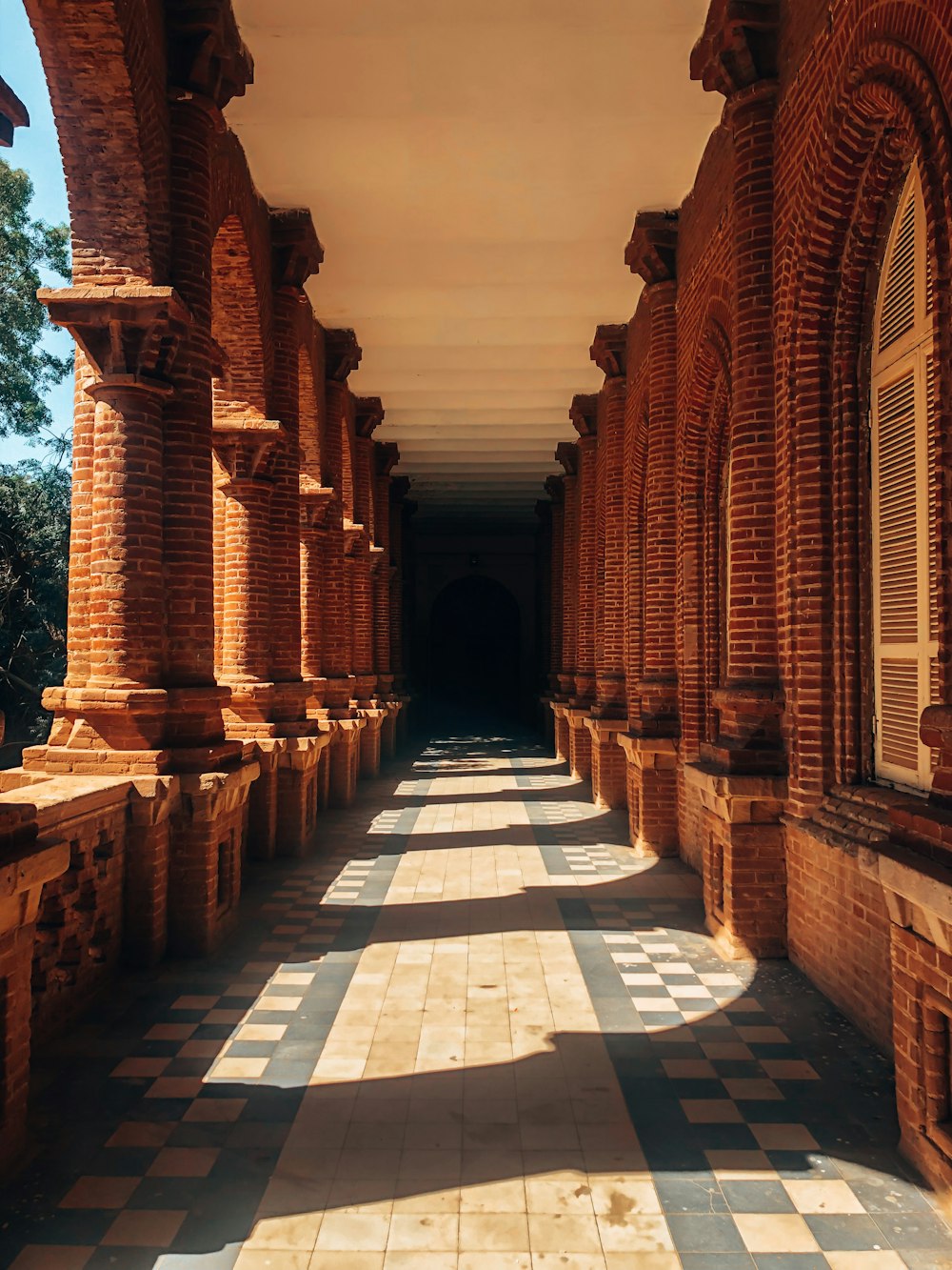 um longo corredor forrado com pilares e janelas de tijolos