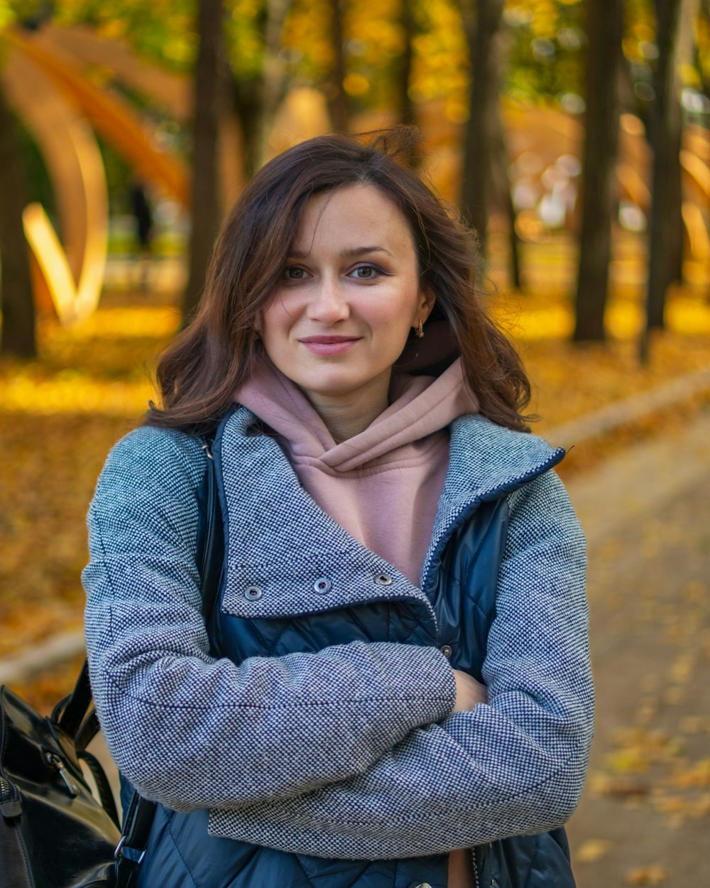 a woman standing in a park with her arms crossed