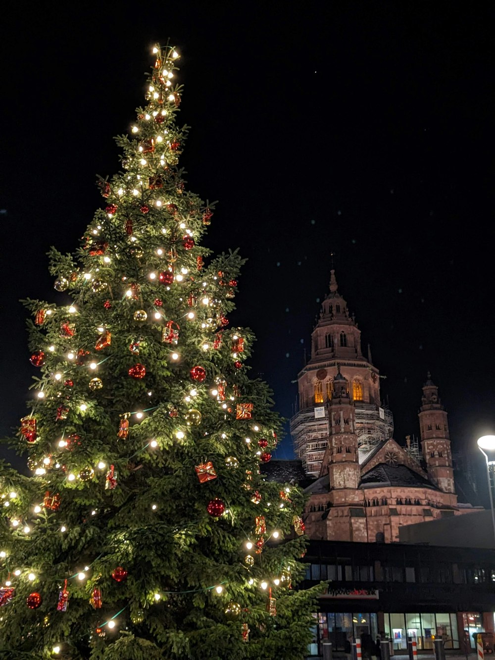 a lit christmas tree in front of a cathedral